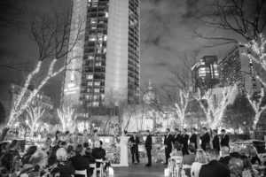 A black and white photo capturing a beautiful wedding ceremony in front of a New York building.