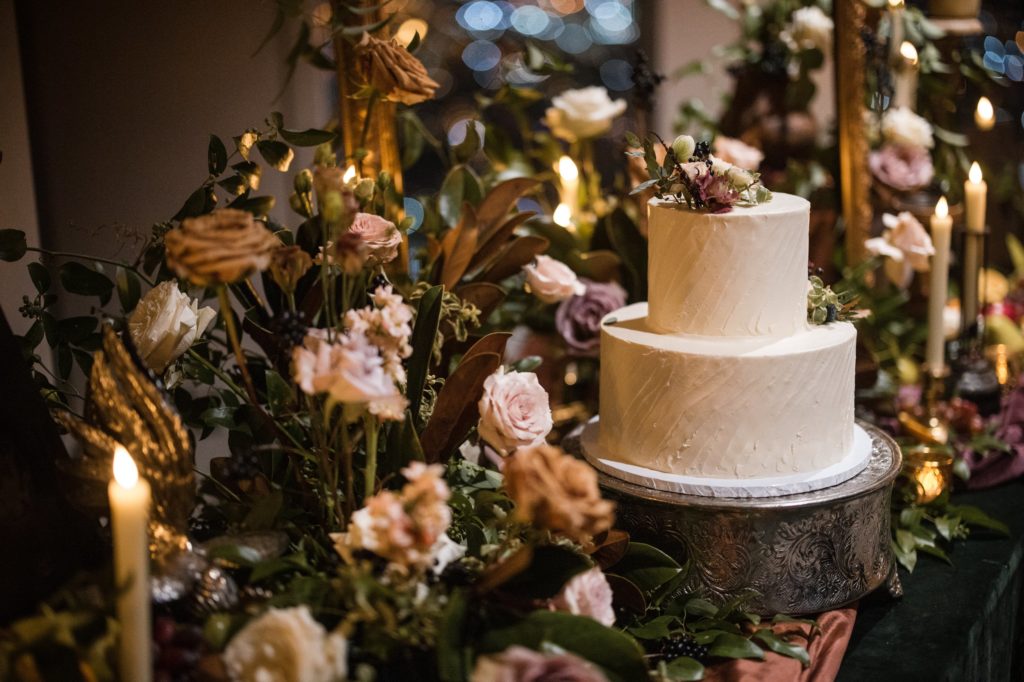 A wedding cake on a table with candles and flowers in New York.