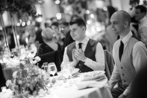 A black and white photo of two men clapping at a wedding in New York.