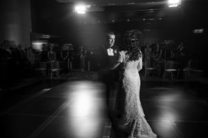 In the romantic glow of a dark room, a bride and groom share their first dance on their wedding day in New York.