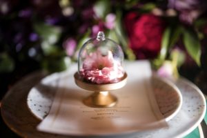 A table setting with a pink flower in a glass dome at a New York wedding.