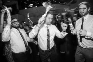 A black and white photo of a group of men dancing at a wedding in New York.