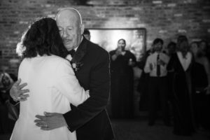 A man and woman hugging in front of a brick wall at their New York wedding celebration.