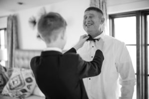 A man in a tuxedo putting on a bow tie for his wedding in New York.