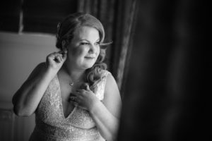A New York bride is putting on her wedding ring in front of a mirror.