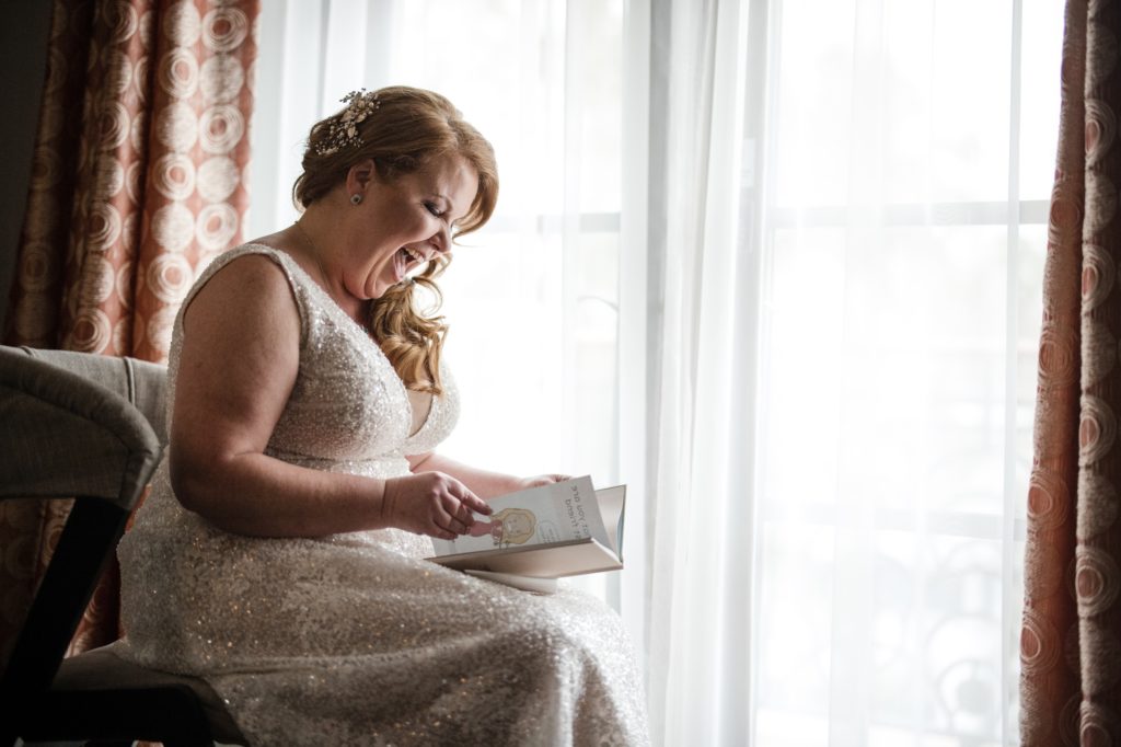 A bride in New York is reading a book in front of a window.