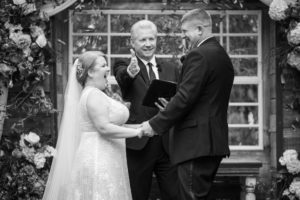 A bride and groom exchange their vows in front of a beautiful garden in New York during their wedding ceremony.