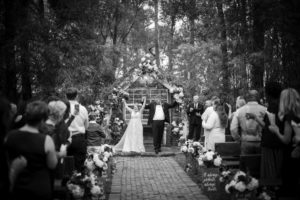 A black and white photo of a wedding ceremony in the woods in New York.
