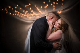 A bride and groom embracing under a veil of lights during their wedding in New York.