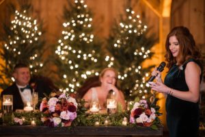 A bride from New York confidently speaking into a microphone at her wedding reception.