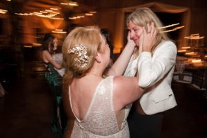 In the heart of New York, two women share a heartfelt embrace at a wedding reception.