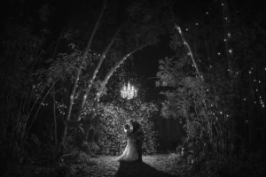 A newlywed couple standing in a dark forest during their wedding in New York.