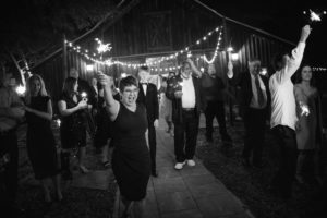 A black and white photo of a group of people holding sparklers at a wedding in New York.