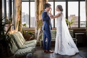 A bride and groom embracing each other in front of a window at their New York wedding.