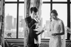 A bride and groom reading their vows in front of a window in New York during their wedding.