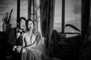 A bride and groom sitting in front of a window on their wedding day in New York.