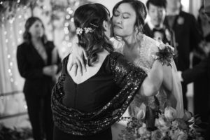 A black and white photo capturing the heartfelt embrace between a bride and her mother on their wedding day in New York.