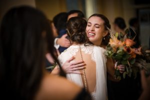 A bride hugging her bridesmaid at a wedding reception in New York.