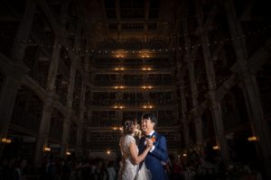 In the enchanting setting of a New York library at night, a bride and groom share their first dance as husband and wife during their romantic wedding celebration.