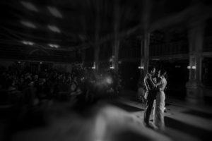 A bride and groom from New York dance in a dark room at their wedding.