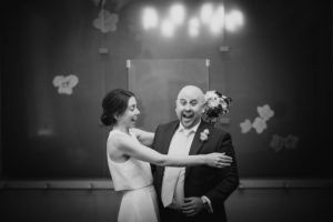 A bride and groom hugging in a black and white photo on their wedding day.