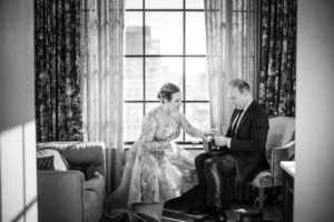 A new york couple celebrating their wedding day, sitting in front of a window.