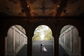 A newlywed couple standing on a staircase in Central Park after their New York wedding.