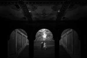 A black and white photo of a couple standing on stairs in Central Park, New York.