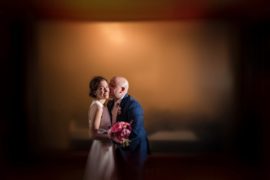 A bride and groom posing in front of a blurred background at their New York wedding.