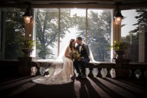 A bride and groom sitting on a bench in front of a window, capturing the essence of their New York wedding.