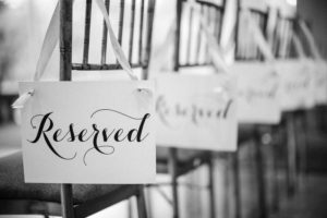 A black and white photo of chairs with reserved signs at a wedding in New York.