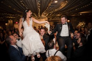 In New York, a bride and groom are being carried by a group of people at their wedding.