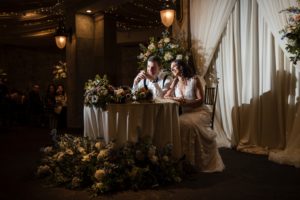A bride and groom sitting at a table at a wedding reception in New York.