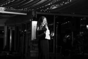 Black and white photo of a woman holding a microphone at a wedding in New York.
