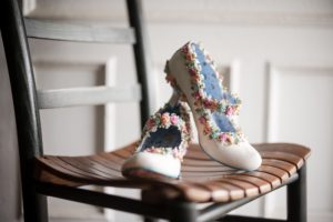 A pair of white wedding shoes on a wooden chair in New York.