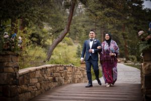 A bride and groom walking down a walkway in the woods during their New York wedding.