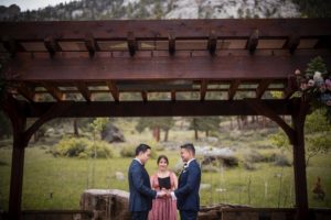 A bride and groom exchange vows under a pergola in the New York mountains.