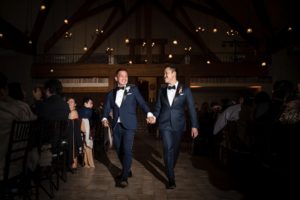 Two grooms walking down the aisle at a wedding ceremony in New York.