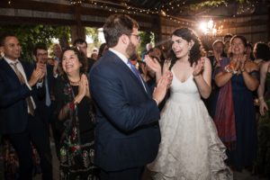 A bride and groom clapping at their wedding reception in New York.