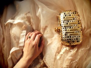 A woman's hand resting on a gold clutch at a wedding in New York.