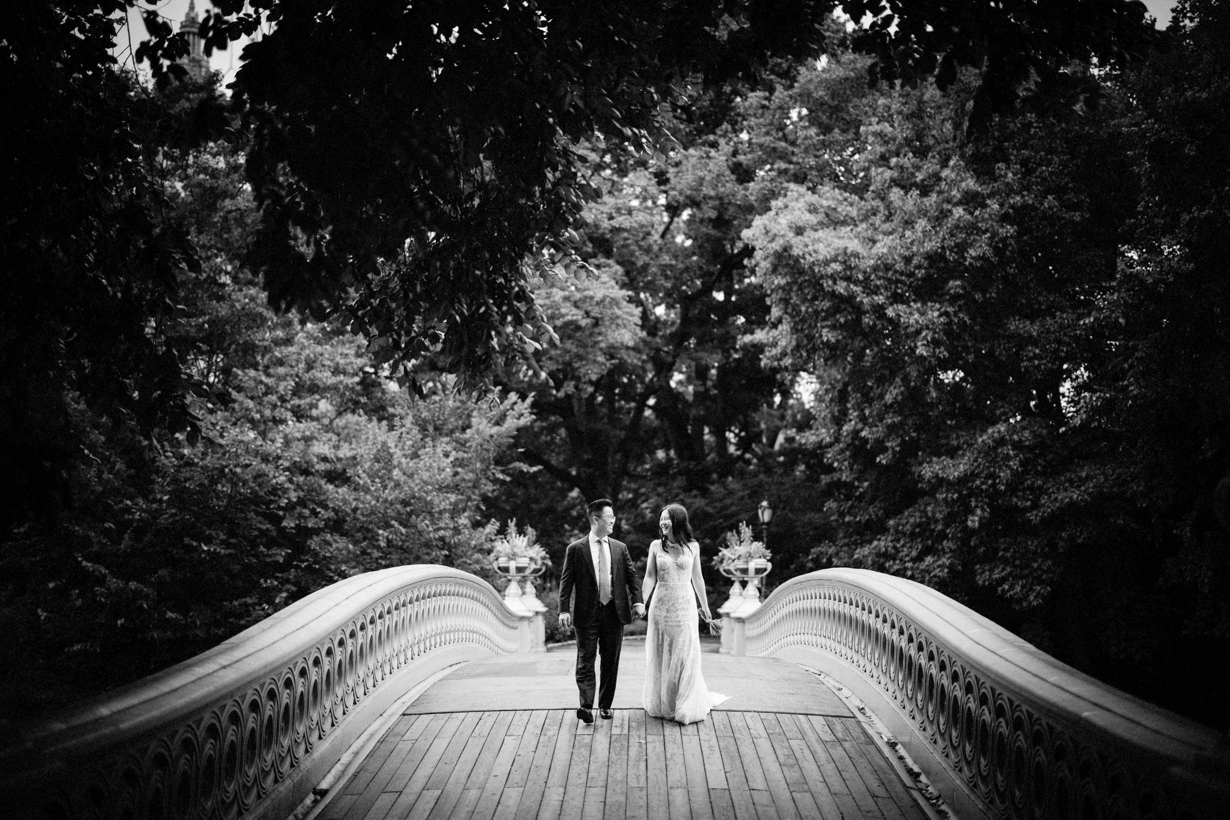 wedding couple walking across bow bridge in central park
