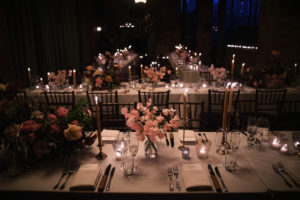 At a wedding in New York, a table is elegantly adorned with candles and flowers.