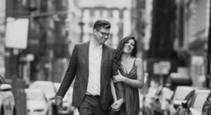 A couple holding hands and walking down a cobblestone city street.