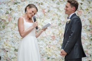 A bride holding a microphone as she reads her vows in front of her husband.