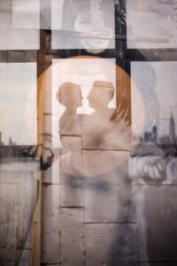 The silhouette of a couple dancing with an industrial style window over top.
