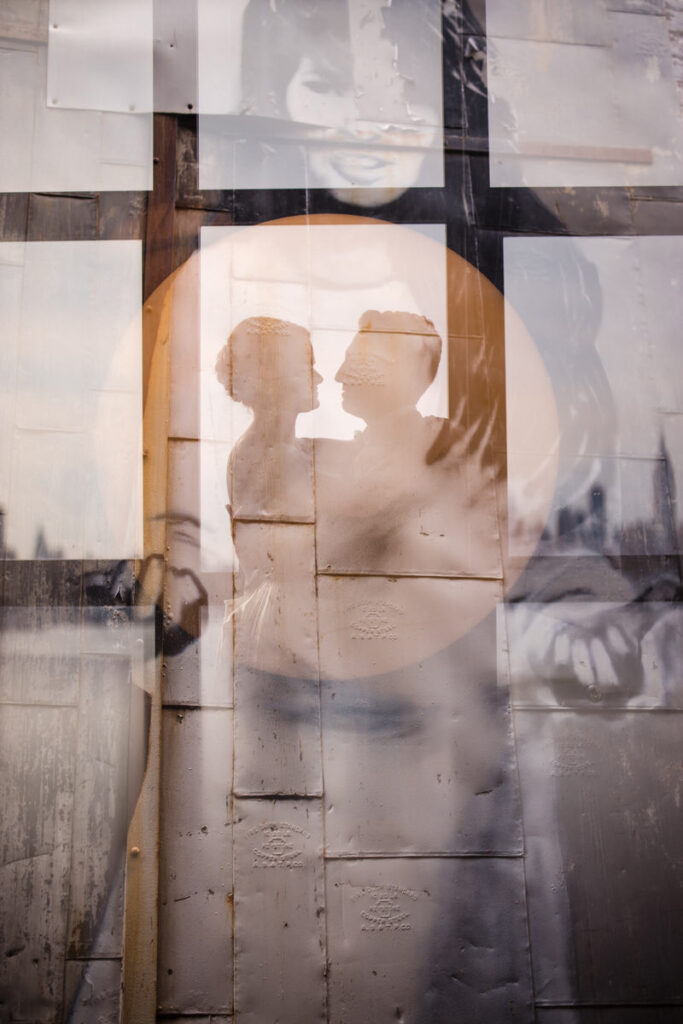 The silhouette of a couple dancing with an industrial style window over top.