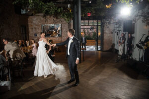 A bride and groom during their first dance with their guests watching.