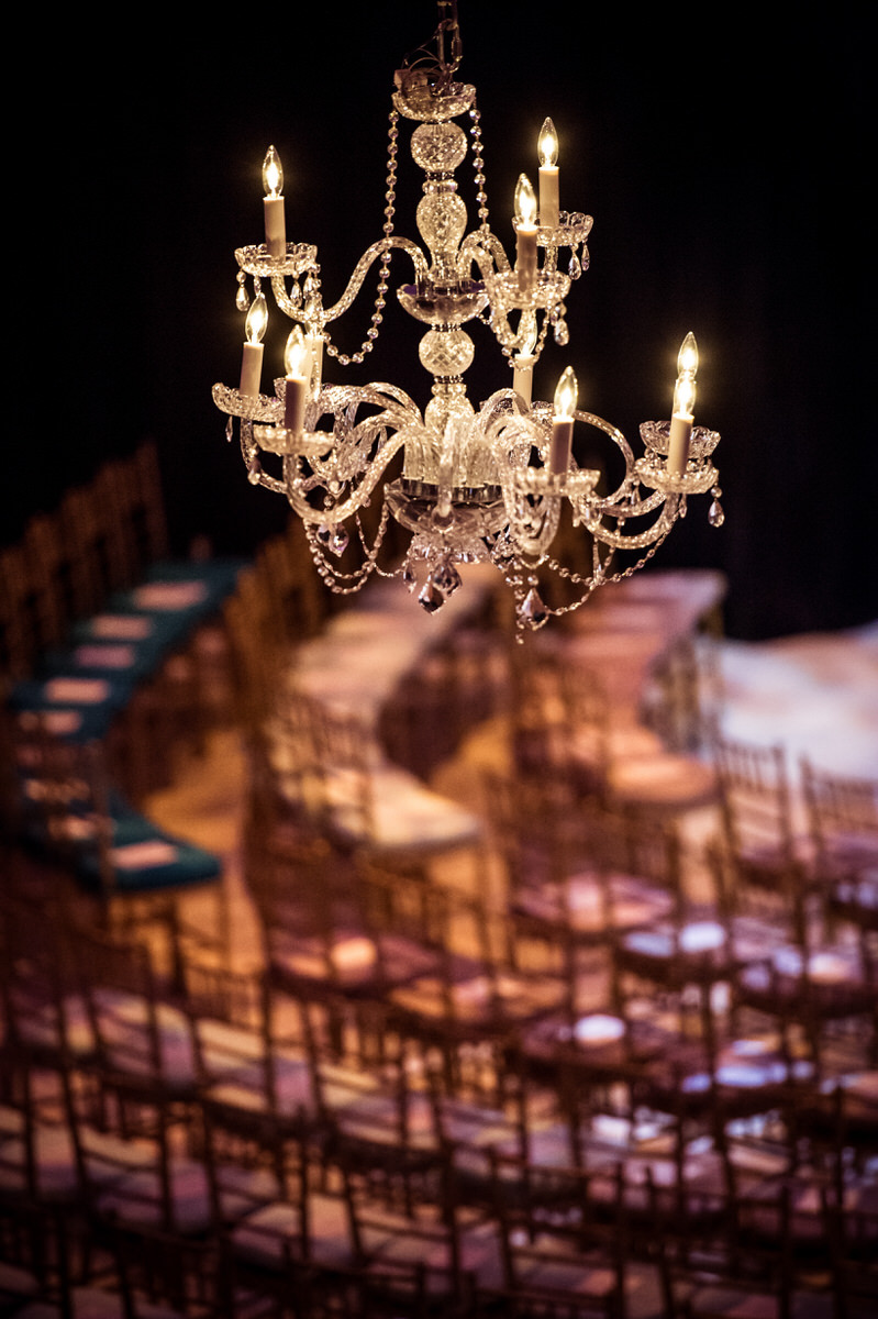 A chandelier hanging over rows of chairs set up in a theater.
