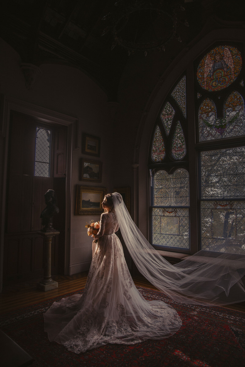 A bride slightly leaning back as her veil flows behind her. 