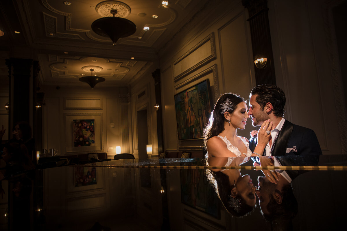 A romantic and intimate moment with a bride and groom reflected on a polished surface, surrounded by soft lighting and elegant interior decor.